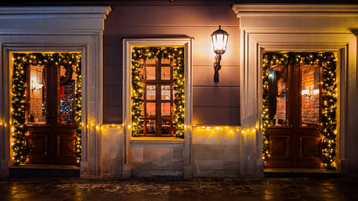 Lit garlands framing the doors and windows of a restaurant facade at night