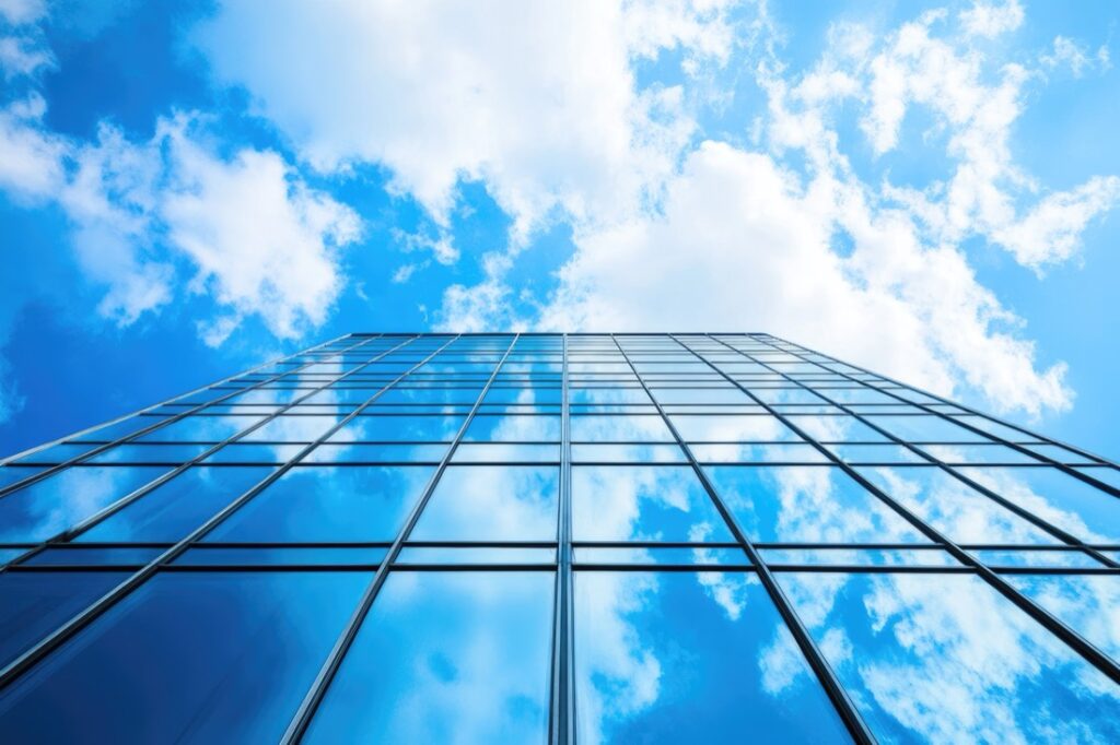 Glass skyscraper reflecting clouds and blue sky